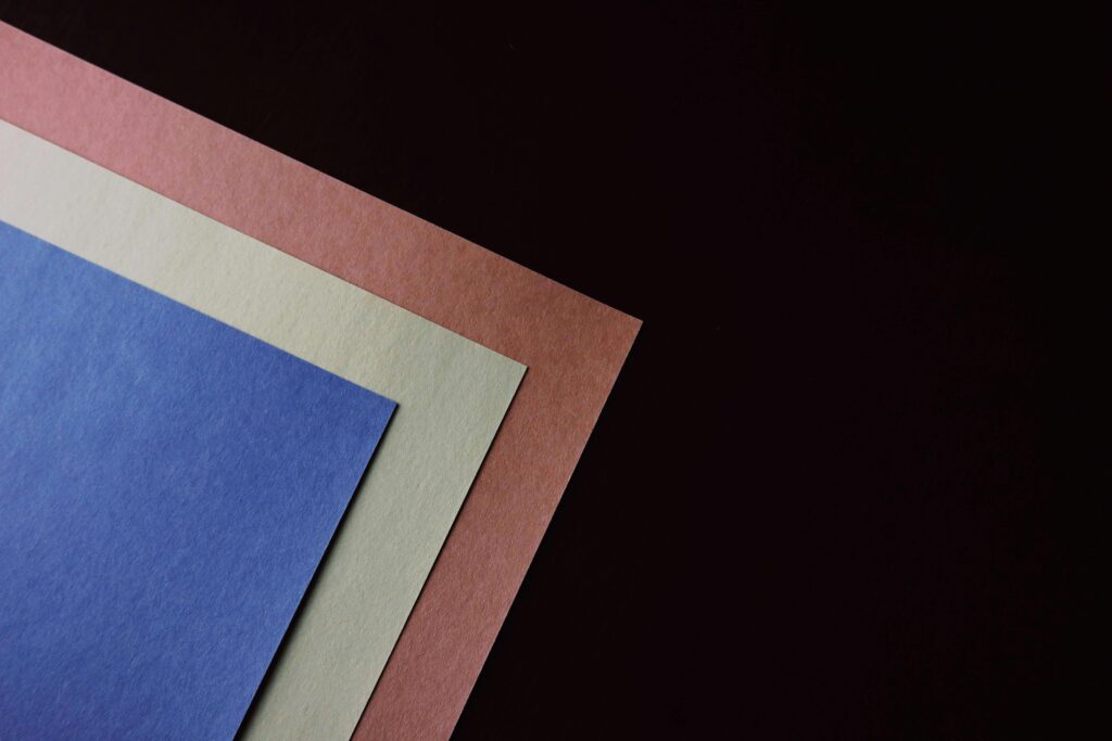 Papier A minimalistic arrangement of colored paper sheets on a black surface, offering vibrant contrasts.