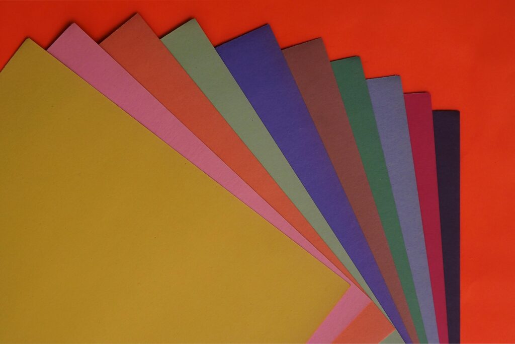 Papier A vibrant flat lay of assorted colored papers on a red surface, great for creative projects.