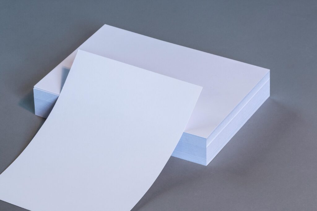 Papier A high-quality image showing blank white paper sheets stacked on a neutral gray surface.